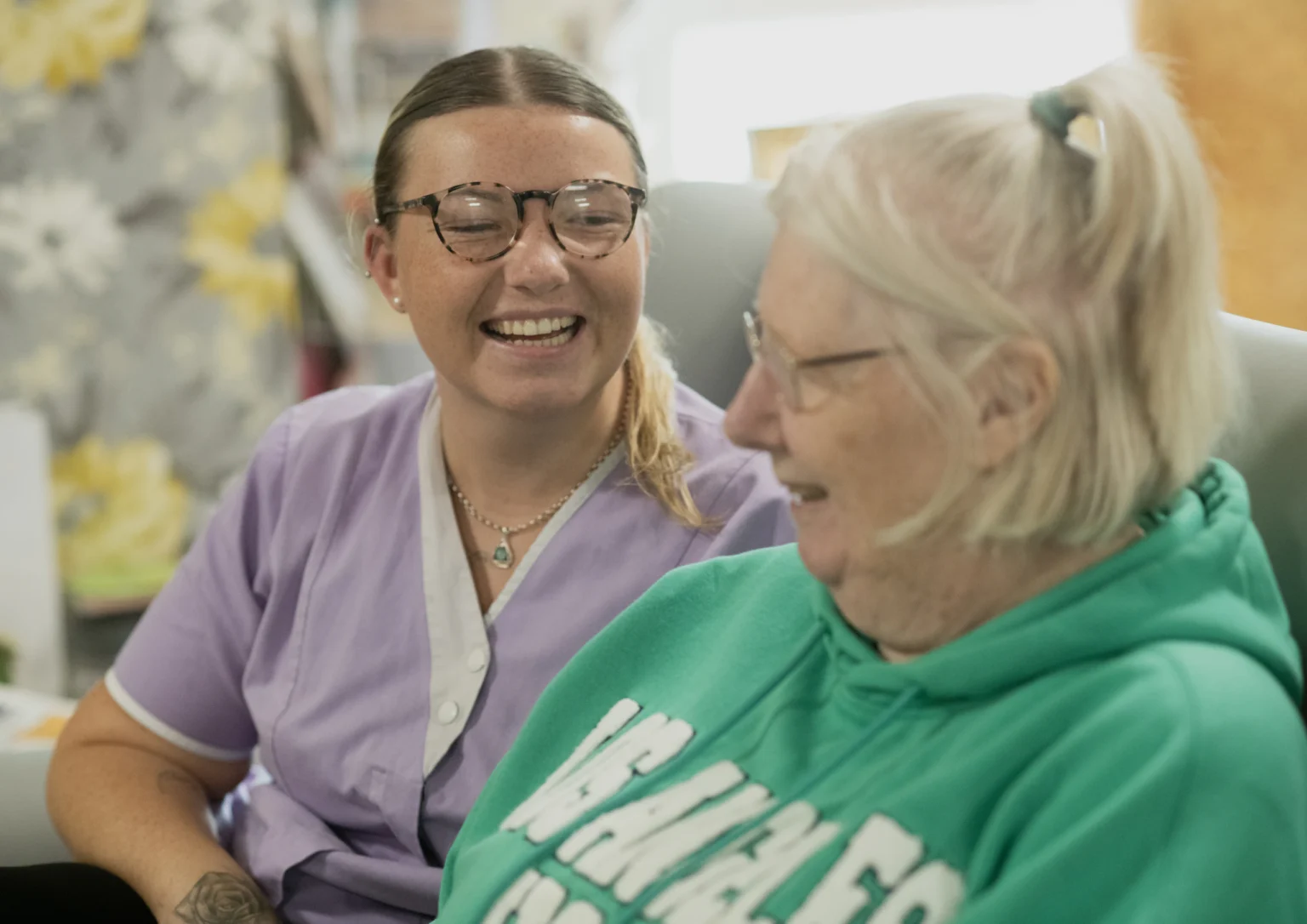 Carer and elderly woman laughing together